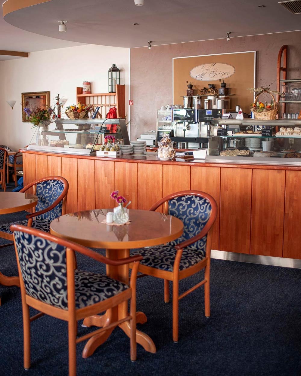 Gemütliches Café mit hölzernen Tischen und blauen Stühlen, Theke im Hintergrund