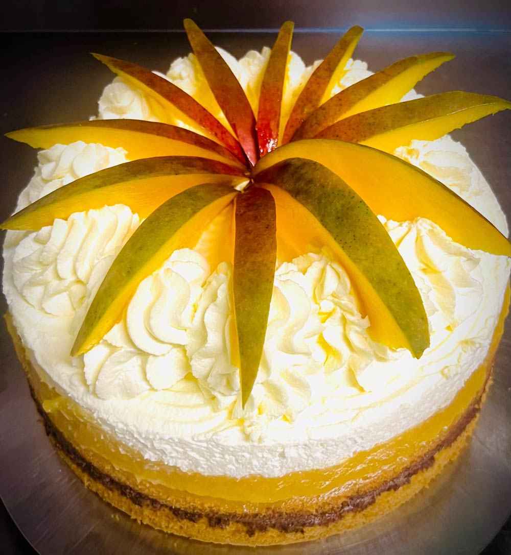 Eine Torte mit Mangoscheiben dekoriert, luftigem Sahnehäubchen und gelber Füllung