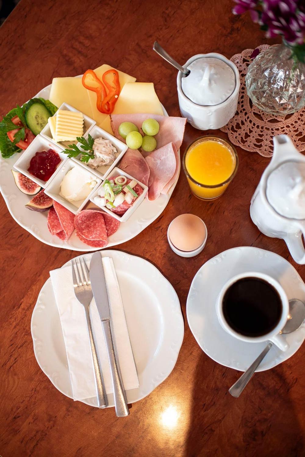 Ein liebevoll angerichtetes Frühstück mit Wurst, Käse, Brötchen und frischem Obst